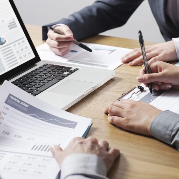 Business professionals working together at office desk, hands close up pointing out financial data on a report, teamwork concept